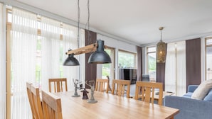 Un comedor con una mesa de madera, sillas e iluminación colgante.