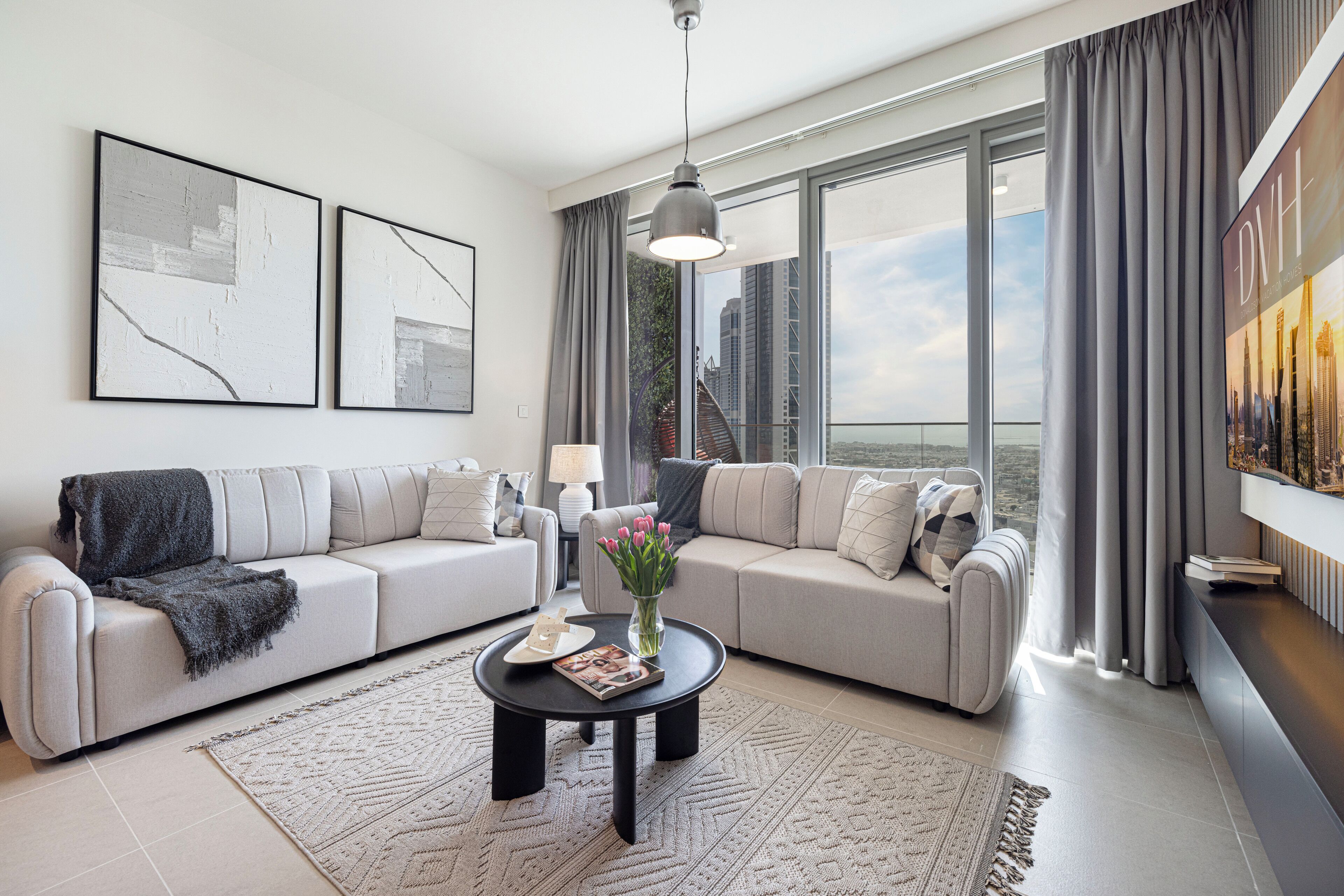 A modern living room with two sofas, a coffee table, and a large window with curtains.