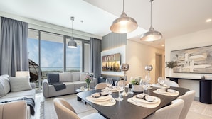 A modern living room with a dining area, large windows, and a cityscape view. - Downtown Dream Sea View Near Dubai Mall (Dubai)