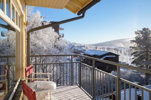 Uma varanda com vista para árvores e casas cobertas de neve.