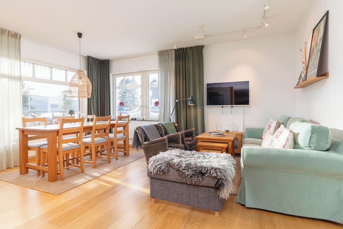 A spacious living area with a dining table, chairs, a sofa, and a TV.