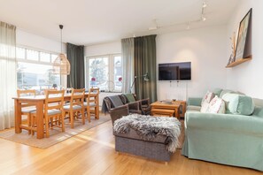 A spacious living area with a dining table, chairs, a sofa, and a TV.