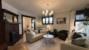 A living room with a fireplace, two sofas, a coffee table, and a chandelier. - Historic Elegance in Prime Location! (Milwaukee)