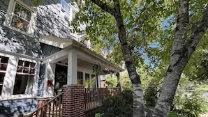 A two-story house with a porch, brick foundation, and a tree in the foreground. - Historic Elegance in Prime Location! (Milwaukee)