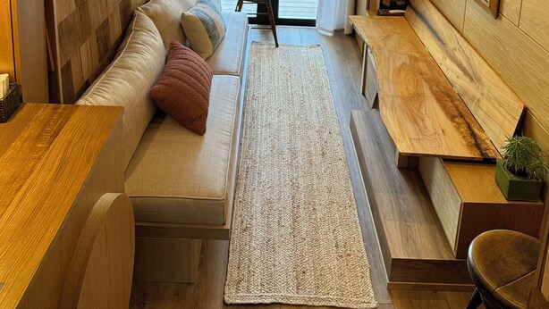 A modern interior with a sofa, rug, wooden accents, and a view through a door. - "City Hideaway: Off-Grid Luxe" (Lancaster)