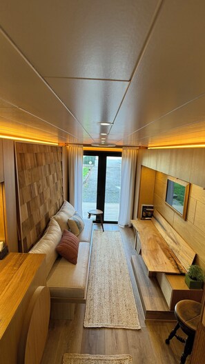 Ein modernes Interieur mit Sofa, Teppich, Holzelementen und Blick durch eine Tür.