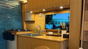 A modern kitchen with wooden cabinets, a stainless steel sink, and a built-in oven. - "City Hideaway: Off-Grid Luxe" (Lancaster)