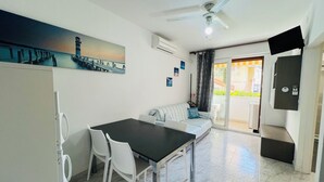 A modern kitchen with a dining table, chairs, a sofa, and a ceiling fan. - Bright Apartment 150mt From the sea (San Michele al Tagliamento)