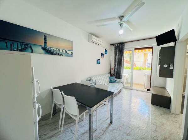 Une cuisine moderne avec une table à manger, des chaises, un canapé et un ventilateur de plafond.
