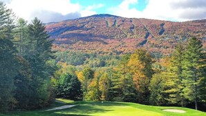 Ein Golfplatz mit Blick auf einen bewaldeten Berg.
