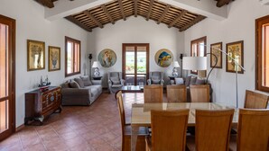 A spacious living room with a high wooden ceiling, a dining area with a glass table, and multiple seating options. - Villa sui Colli Ericini con Piscina by Wonderful Italy (Erice)