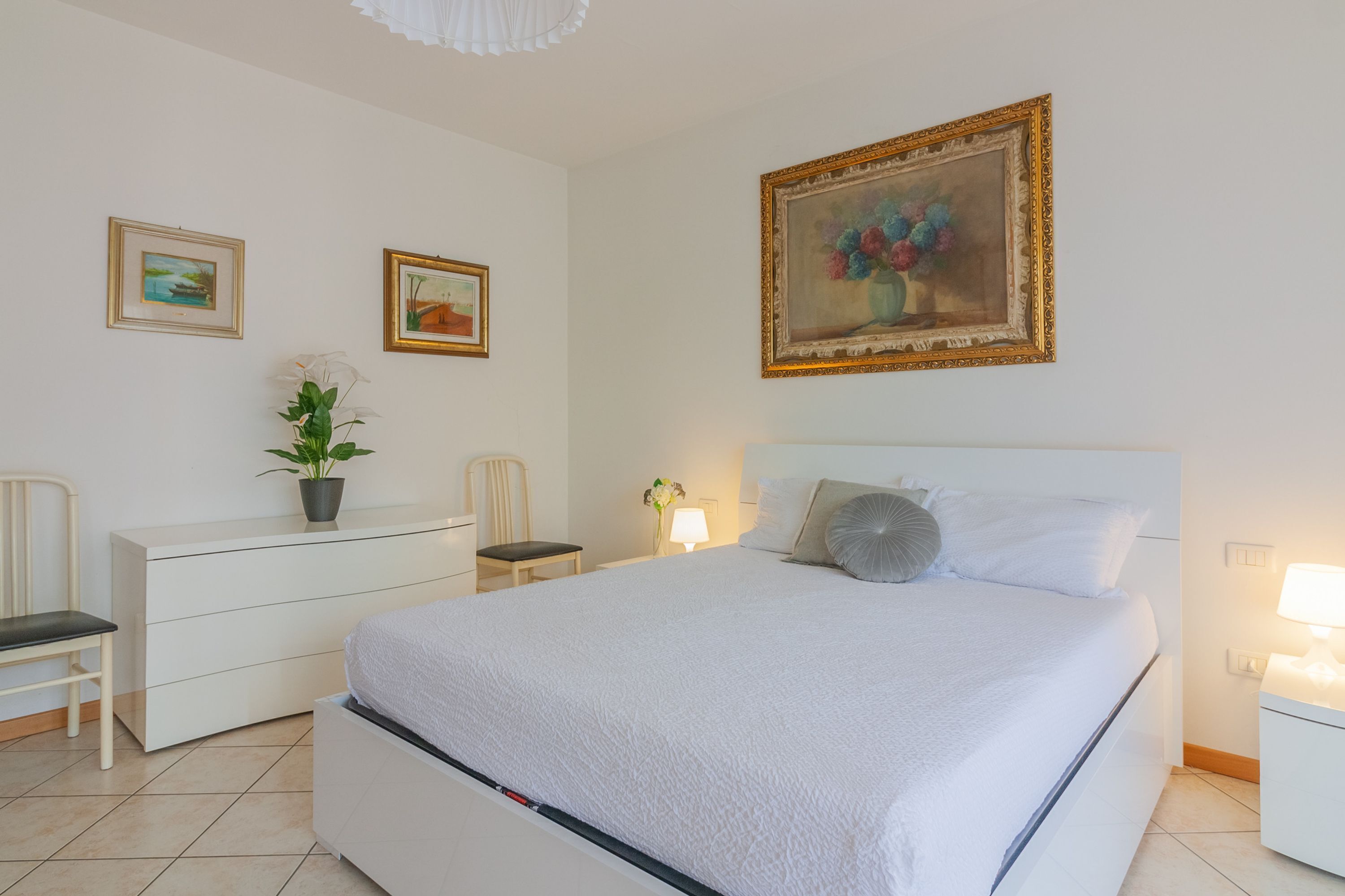 A neatly arranged bedroom with a bed, bedside tables, a dresser, and chairs.