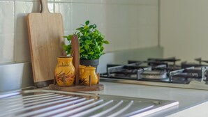 Una encimera de cocina con una tabla de cortar de madera, una planta en maceta y recipientes de cerámica amarillos.