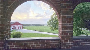 Ein Backsteinbogen mit Blick auf einen roten Bauernhof und ein grünes Feld.