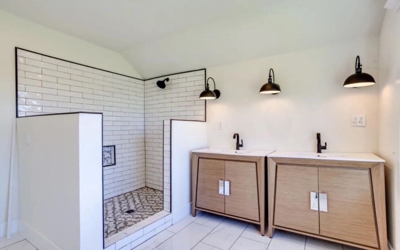 Ein modernes Badezimmer mit Dusche, zwei Waschbecken und Holzschränken.
