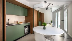 A modern kitchen with green cabinets, a white dining table, and a built-in oven. - Settimo Apartment With Terrace by Wonderful Italy (Palermo)