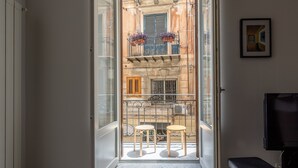 An open door leading to a balcony with two stools, a TV, and a framed picture on the wall. - Metam Apartment in the City Center by Wonderful Italy (Palermo)