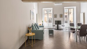 A spacious living area with a sofa, a small table, a TV, and a dining table with chairs. - Metam Apartment in the City Center by Wonderful Italy (Palermo)