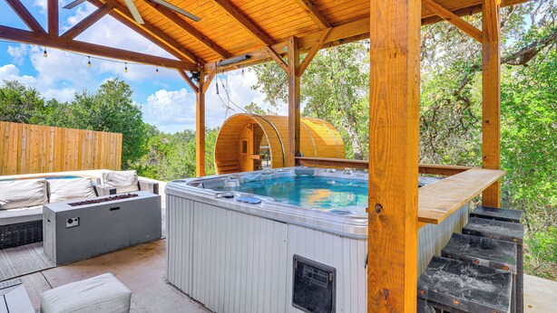 A wooden deck with a hot tub, outdoor seating, and a covered area.