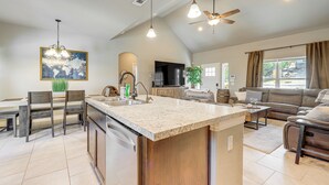A spacious kitchen with a large island, a dining area with chairs, a sofa, and a TV.