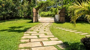A stone pathway leading to a wooden gate in a well-maintained garden. - Nuwans Countryside Hideaway (Tangalle)