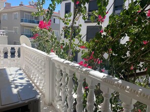 A balcony with a white balustrade and pink flowers. - Çeşme'de Marinaya ve Alışveriş Merkezlerine Yakın 2 Oda 1 Salon Daire (İzmir)