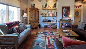 Un salon chaleureux avec un plafond en bois, une grande armoire, un canapé, une table basse et un tapis.