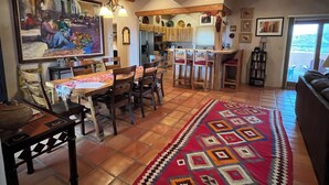 Un vaste espace de vie agrémenté d’un grand tapis, de meubles en bois et d’une cuisine située au fond de la pièce.