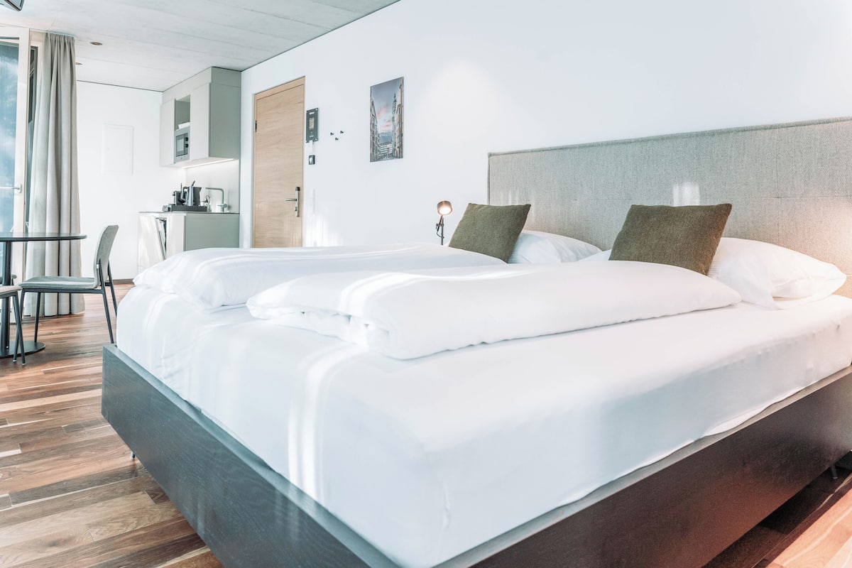 Ein modernes Hotelzimmer mit einem großen Bett, einem Schreibtisch und einer Küchenzeile.