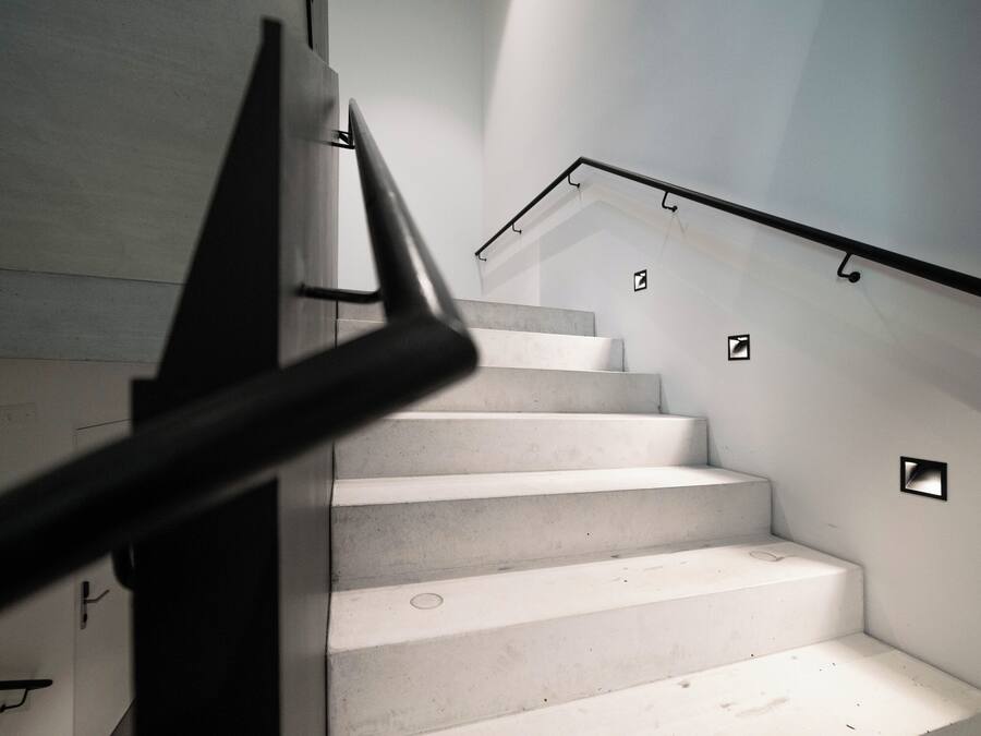A staircase with a modern design, featuring a metal handrail and a glass railing.