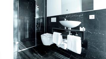 A modern bathroom with a black marble sink, white toilet, and glass shower enclosure.