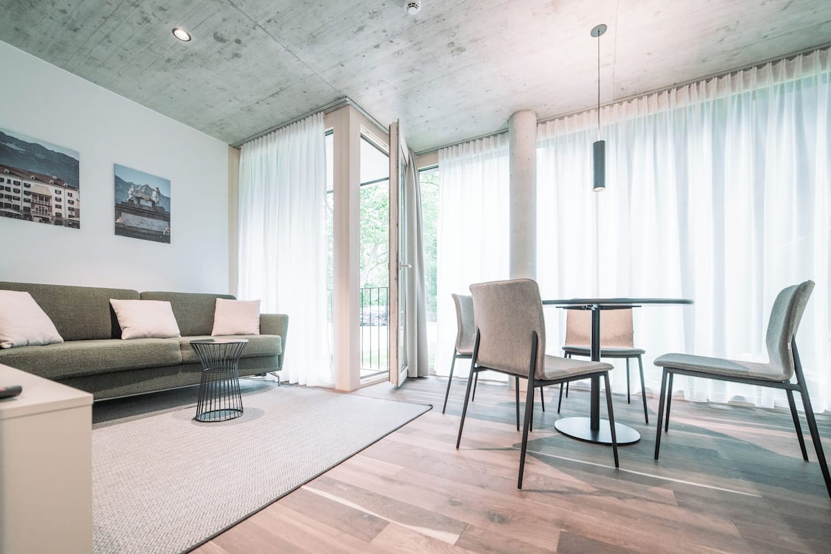Ein modernes Wohnzimmer mit Sofa, Couchtisch und einem Essbereich mit Stühlen und Tisch.
