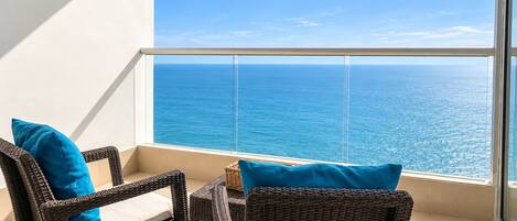 A balcony with wicker furniture and a view of the ocean.