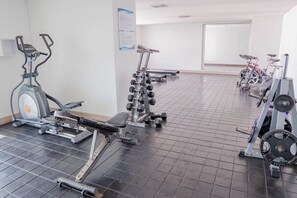 Un gimnasio con equipo de ejercicio, incluyendo cintas de correr, bicicletas estáticas y máquinas de pesas.