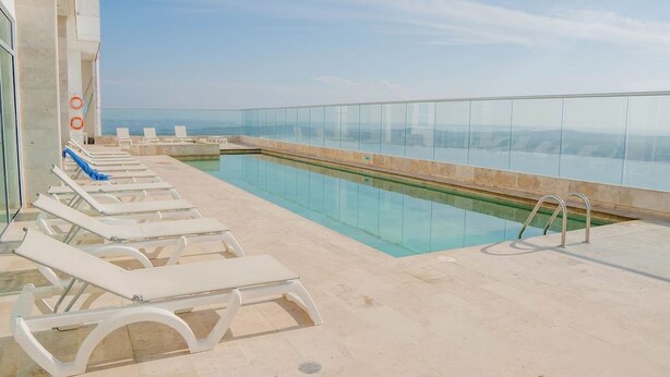 A rooftop pool with lounge chairs and a glass balustrade. - U-GO Palmetto Sunset Junto al Mar (Cartagena)