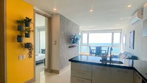 A modern kitchen with a large island, a dining area with a view, and a bright yellow accent wall. - U-GO Palmetto Sunset Junto al Mar (Cartagena)