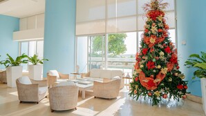 A spacious lobby with wicker furniture, large windows, and a decorated Christmas tree. - U-GO Palmetto Sunset Junto al Mar (Cartagena)