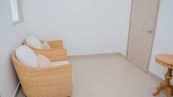 Una habitación con dos sillones de mimbre, una mesa redonda de madera y una puerta.