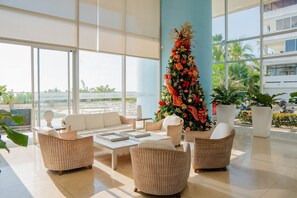 A spacious lobby with wicker furniture, a large Christmas tree, and a view of the outdoors. - U-GO Palmetto Sunset Junto al Mar (Cartagena)