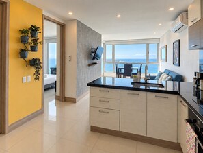 A modern kitchen with a large island, a dining area with a view, and a living space with a sofa and a TV. - U-GO Palmetto Sunset Junto al Mar (Cartagena)