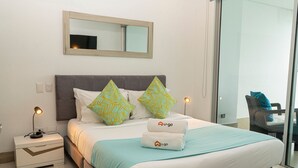 A neatly made bed with a white and blue bedspread, two pillows with a leaf pattern, and a U-go branded towel. - U-GO Palmetto Sunset Junto al Mar (Cartagena)