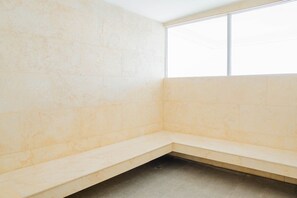 A corner of a room with beige tiled walls and a bench. - U-GO Palmetto Sunset Junto al Mar (Cartagena)