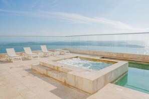Een dakzwembad met oneindige horizon, een jacuzzi en ligbedden, met uitzicht op een prachtig panorama.