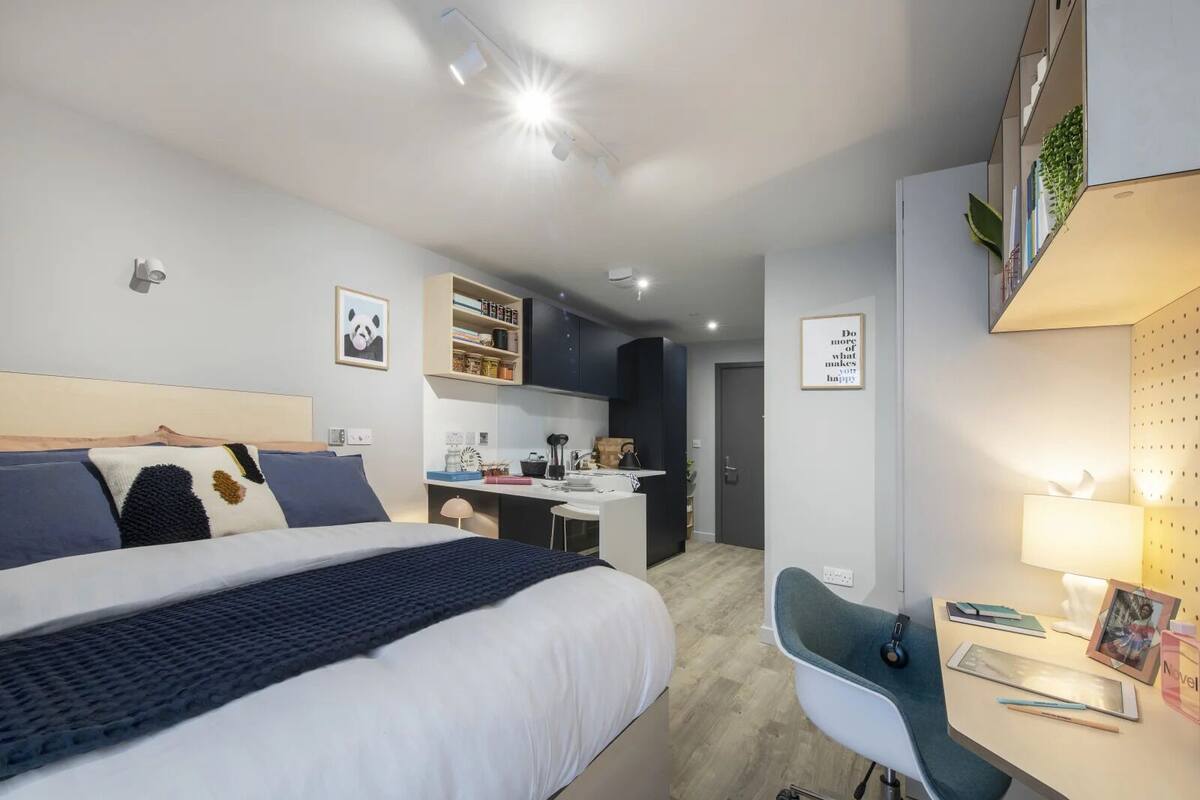 Ein modernes Hotelzimmer mit einem großen Bett, einem Schreibtisch und einer Küchenzeile.