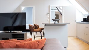 A modern apartment with a TV, sofa, and kitchen area. - Blackhome Wien (Vienna)