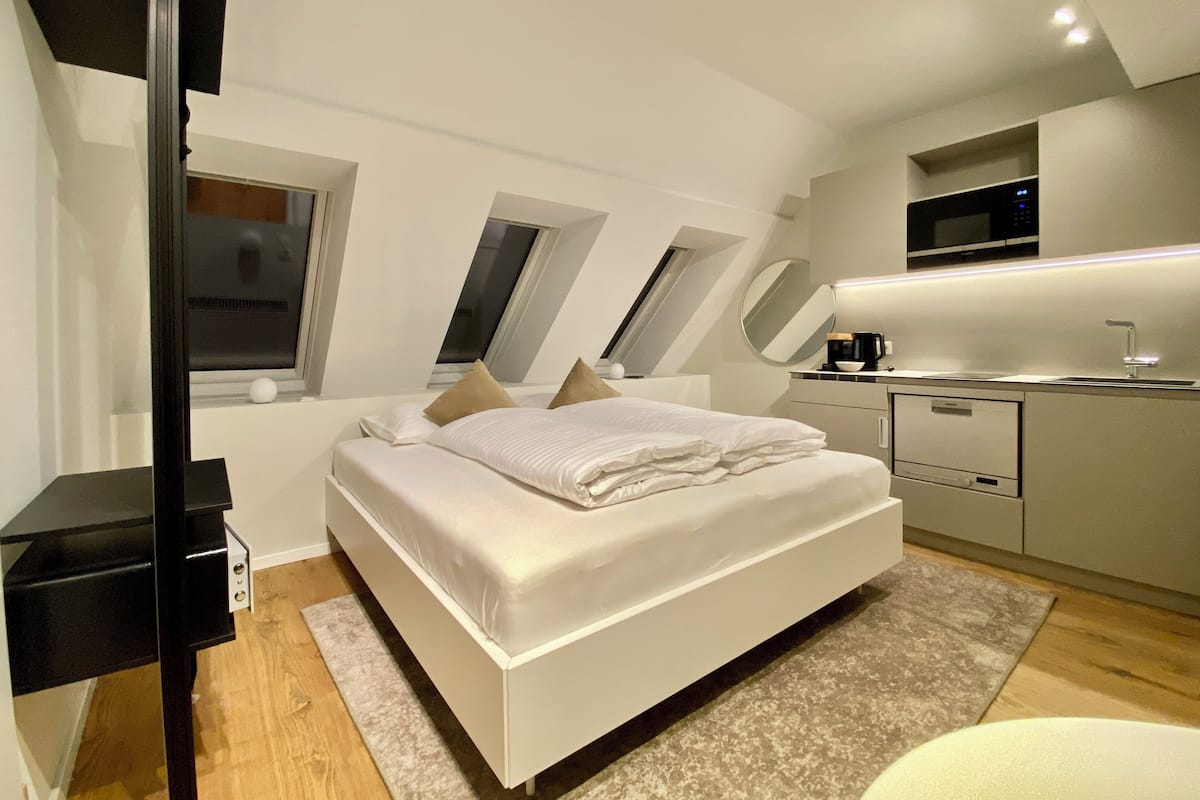 Un dormitorio moderno con una cama grande, un escritorio empotrado y un tragaluz.