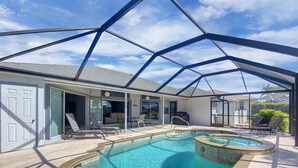 A covered swimming pool area with a glass enclosure, lounge chairs, and a patio with a barbecue. - Hello Summer, full refund*, pool heat, sleeps 6 (Rotonda West)