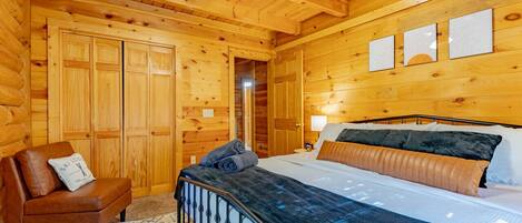 Une chambre dans une cabane en bois, avec un lit, une chaise et un ventilateur de plafond.