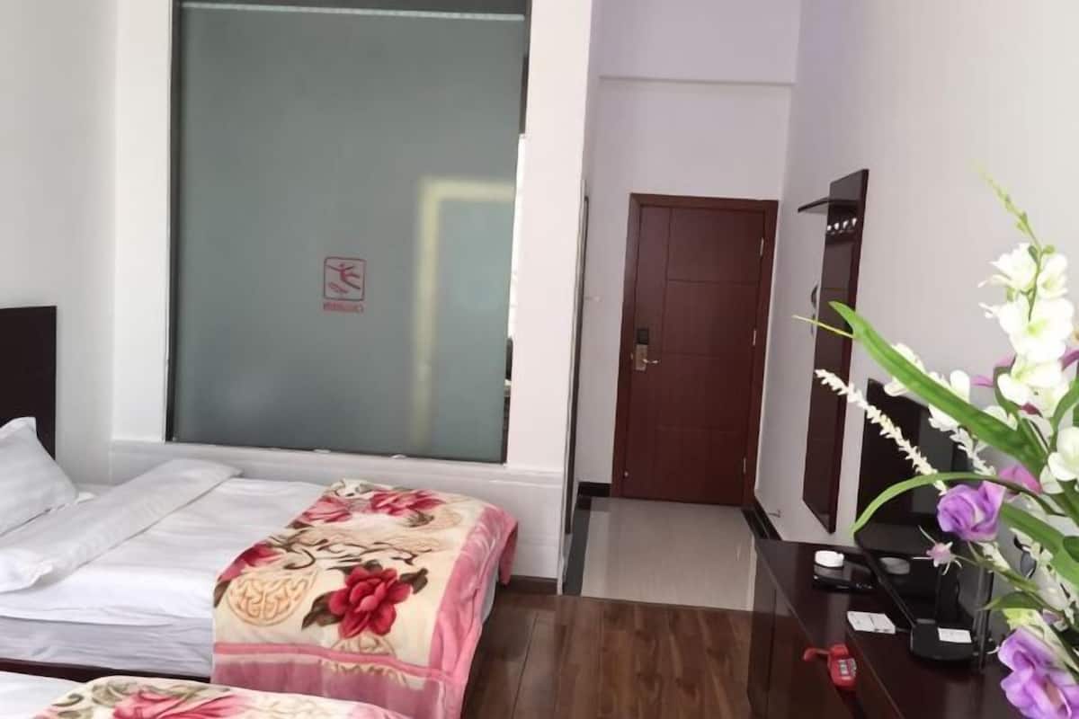 A hotel room with a bed, a desk with a computer, a mirror, and a door.