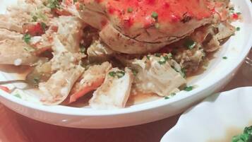 A bowl of crab with a red topping, garnished with herbs.
